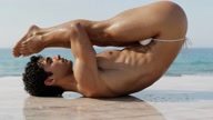 Halasana. Plow Pose. Yogi. Greek athlete, sweaty muscle yoga on wet marble 1m50s